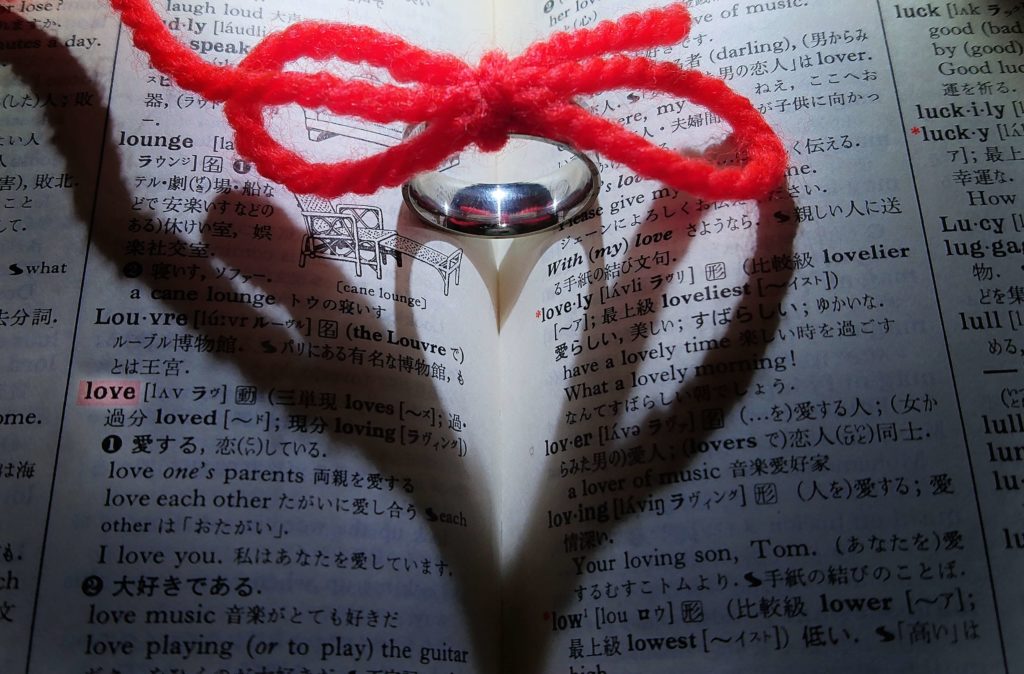 辞書の上に置かれた指輪と指輪に結ばれた赤い紐