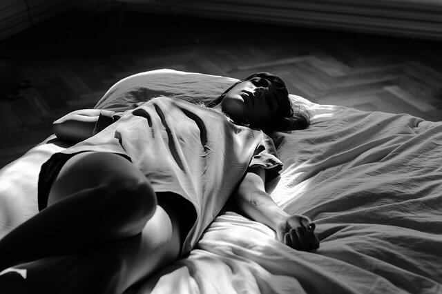 暗い部屋のベッドで眠っている女性
