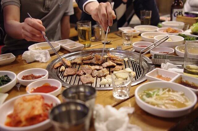 焼肉とお箸で肉をとる男2人の手