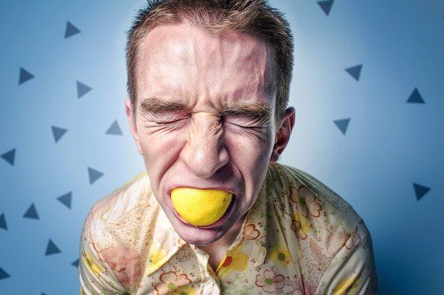 レモンを咥えストレスで顔をしかめている男性