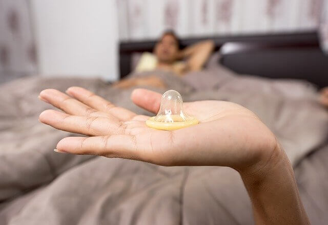 コンドームとベッドに寝転ぶ男性